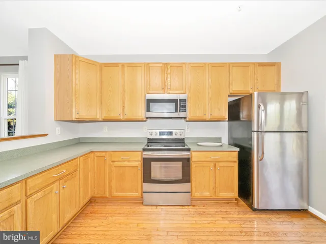 a kitchen with stainless steel appliances granite countertop a sink and cabinets with wooden floor