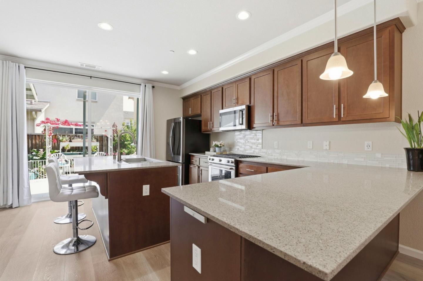 187 Springtime Circle Hollister, CA 95023 - Photo 5 of 19 a kitchen with granite countertop a stove a sink a refrigerator a dining table and chairs with wooden floor