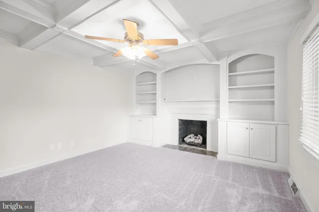 an empty room with a fireplace and fan