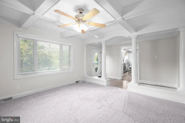 an empty room with chandelier fan and windows