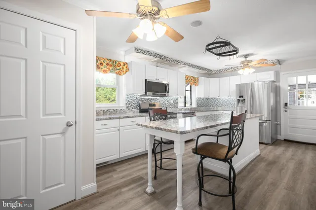 a kitchen with stainless steel appliances granite countertop a stove a sink dishwasher and a refrigerator with wooden floor