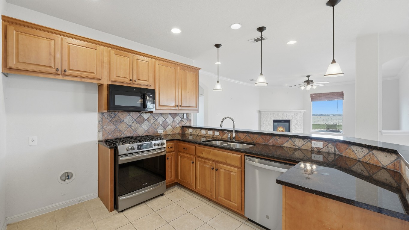 15620 Harry Lind Road Manor, TX 78653 - Photo 23 of 40 a kitchen with stainless steel appliances granite countertop a sink a stove and a microwave oven
