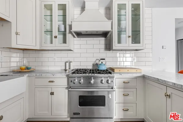 a living room with stainless steel appliances furniture a flat screen tv and kitchen view