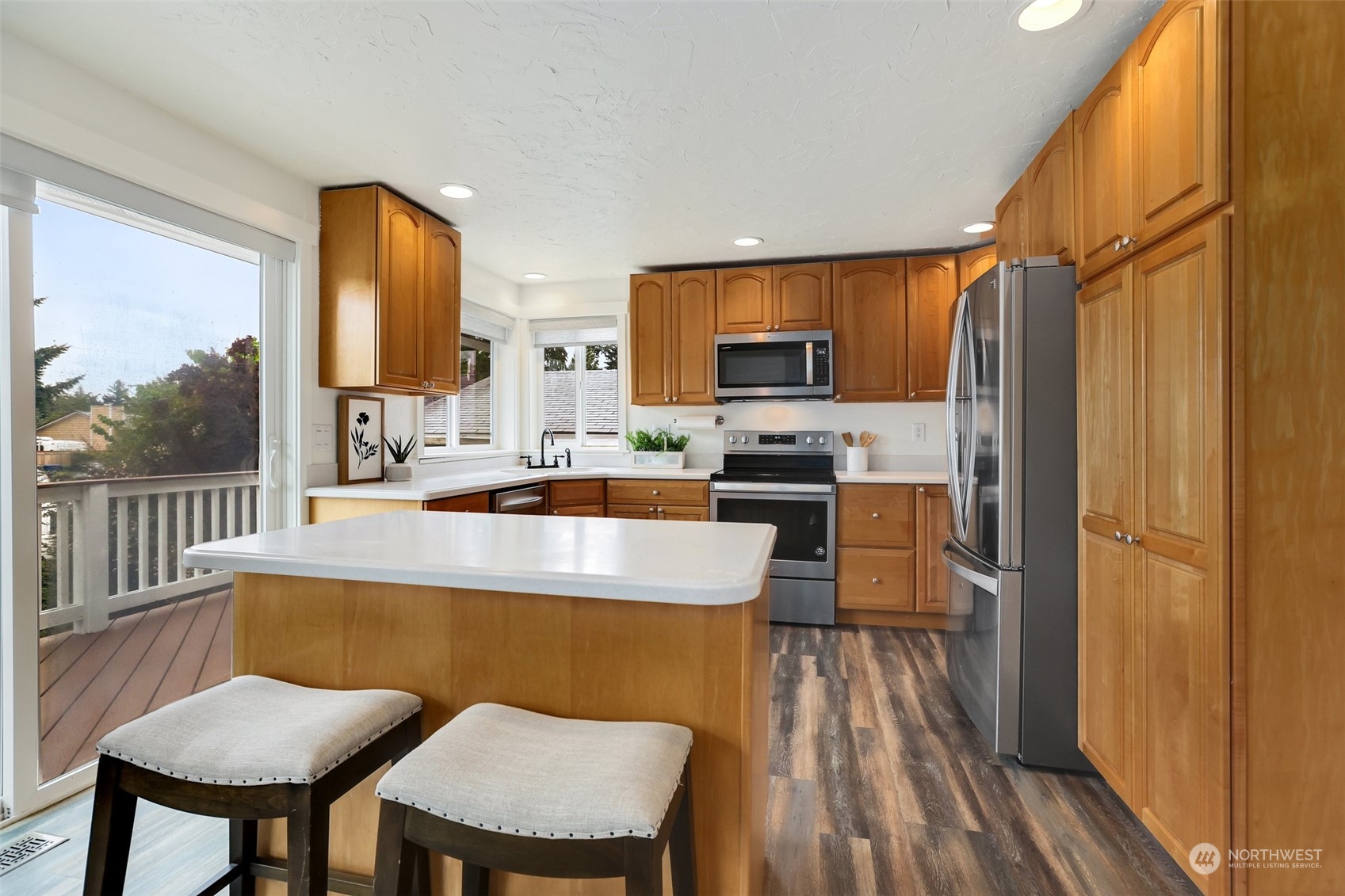 4114 Northeast 22nd Place Renton, WA 98059 - Photo 4 of 28 a kitchen with stainless steel appliances a dining table chairs refrigerator and sink