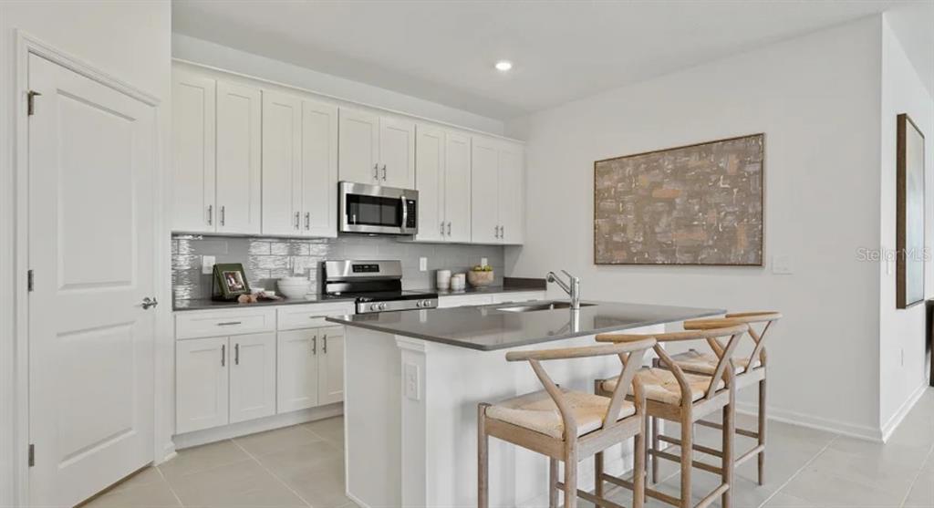4246 St Thomas Way Kissimmee, FL 34758 - Photo 5 of 16 a kitchen with stainless steel appliances a sink a stove a refrigerator cabinets and a window