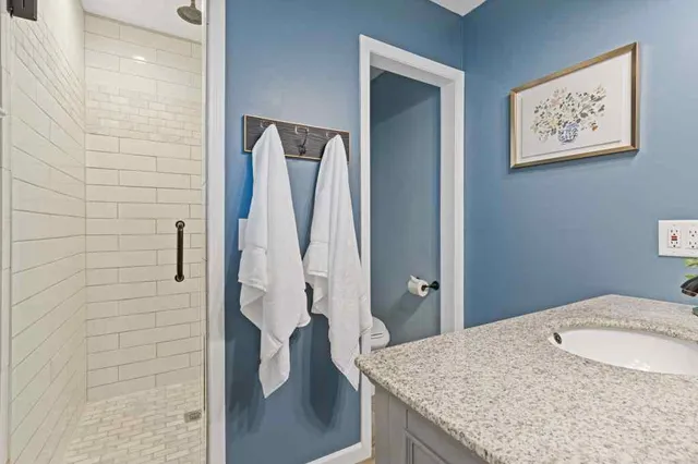 a bathroom with a granite countertop sink a mirror and shower