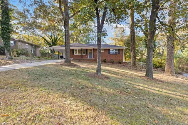 front view of a house with a dirt yard and a large tree