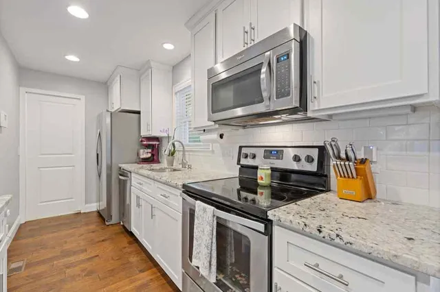 a kitchen with stainless steel appliances granite countertop a sink a stove a microwave a counter space and cabinets