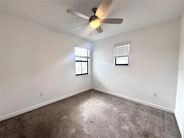an empty room with a window and a fan
