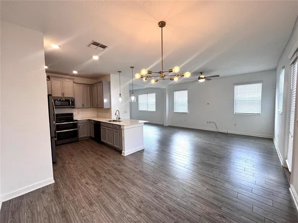 a view of a big room with wooden floor windows and kitchen view