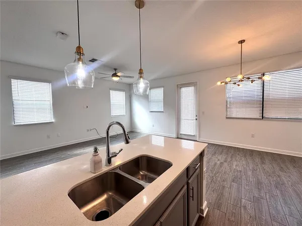a kitchen with a sink a faucet a chandelier and living room view