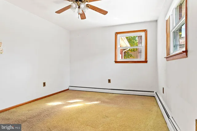 an empty room with a window and ceiling fan