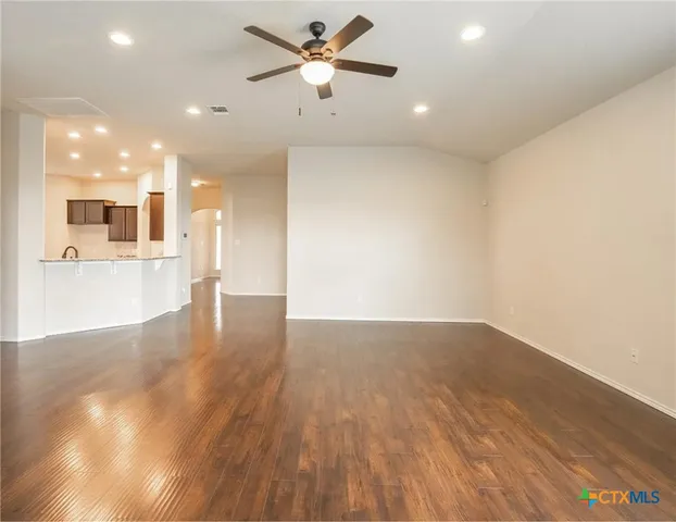a view of a big room with wooden floor and a kitchen space