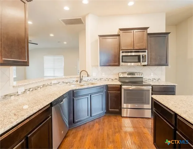 a kitchen with stainless steel appliances granite countertop a sink stove and refrigerator