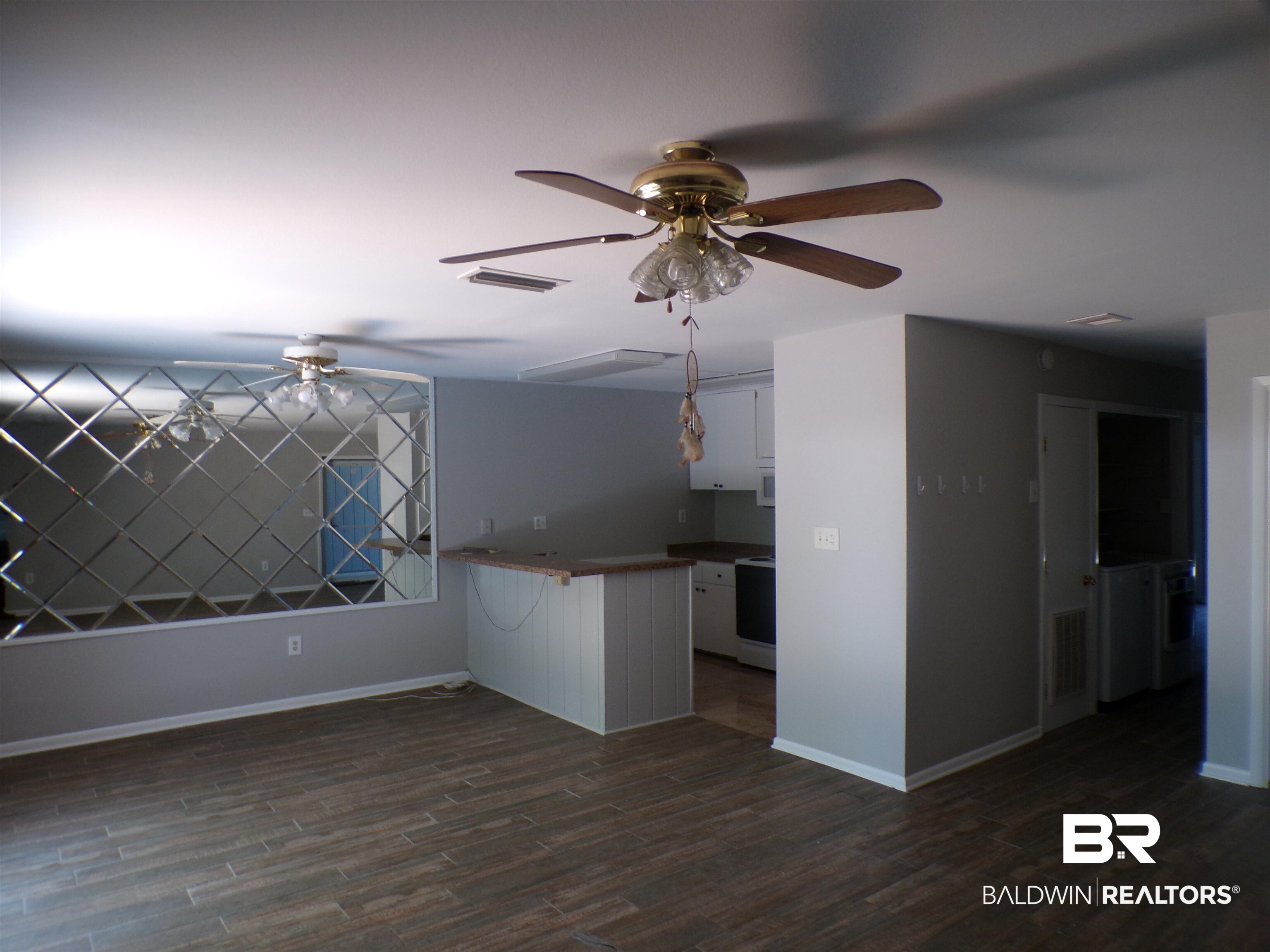 1152 North Alston Street, Unit 1152 Foley, AL 36535 - Photo 6 of 16 Open concept living area featuring wood-finish tile flooring, a decorative mirrored wall panel, and two ceiling fans with integrated lighting