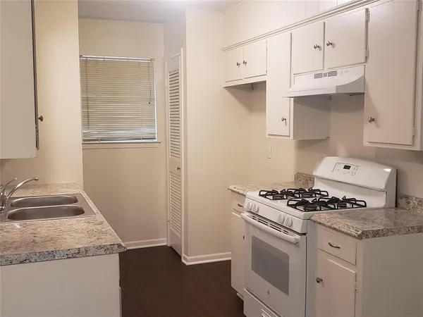 a kitchen with granite countertop a sink stove and cabinets