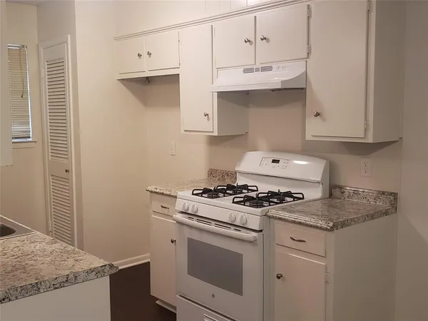 a kitchen with granite countertop white cabinets and white appliances