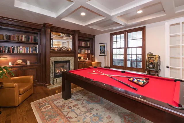 a bedroom with a large bed a flat tv screen and a fireplace with wooden floor