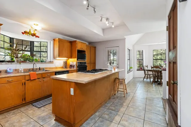 a view of a kitchen with kitchen island granite countertop a large counter top space a sink stainless steel appliances and cabinets