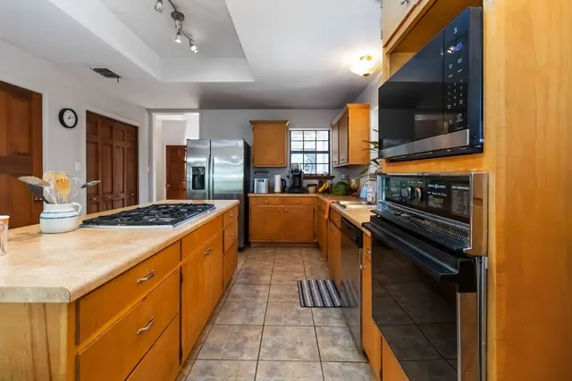 a large kitchen with stainless steel appliances granite countertop a stove and a sink
