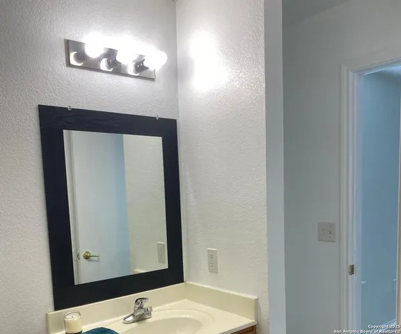a bathroom with a granite countertop sink and a mirror