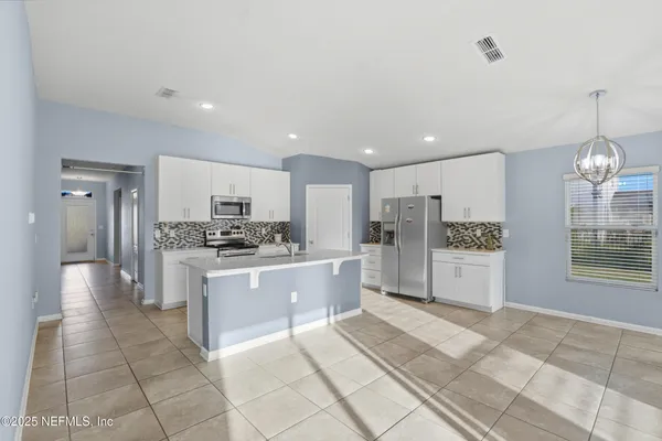 a large kitchen with kitchen island a sink a stove a refrigerator and white cabinets