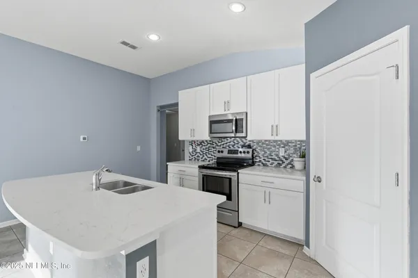 a kitchen with a sink a stove top oven and white stainless steel appliances
