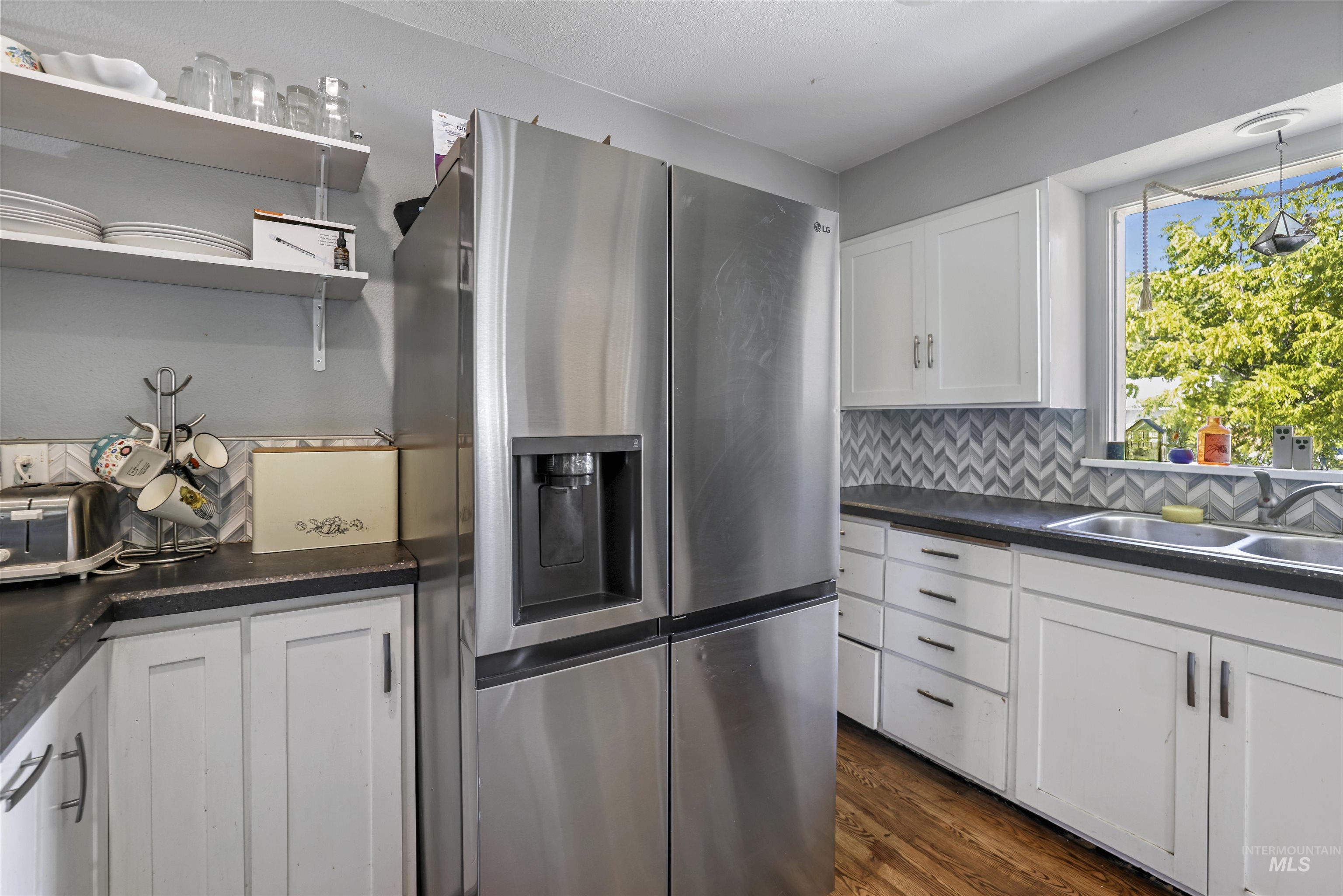 201 West 19th Street Burley, ID 83318 - Photo 12 of 31 Kitchen with stainless steel fridge with ice dispenser, white cabinets, dark countertops, and backsplash