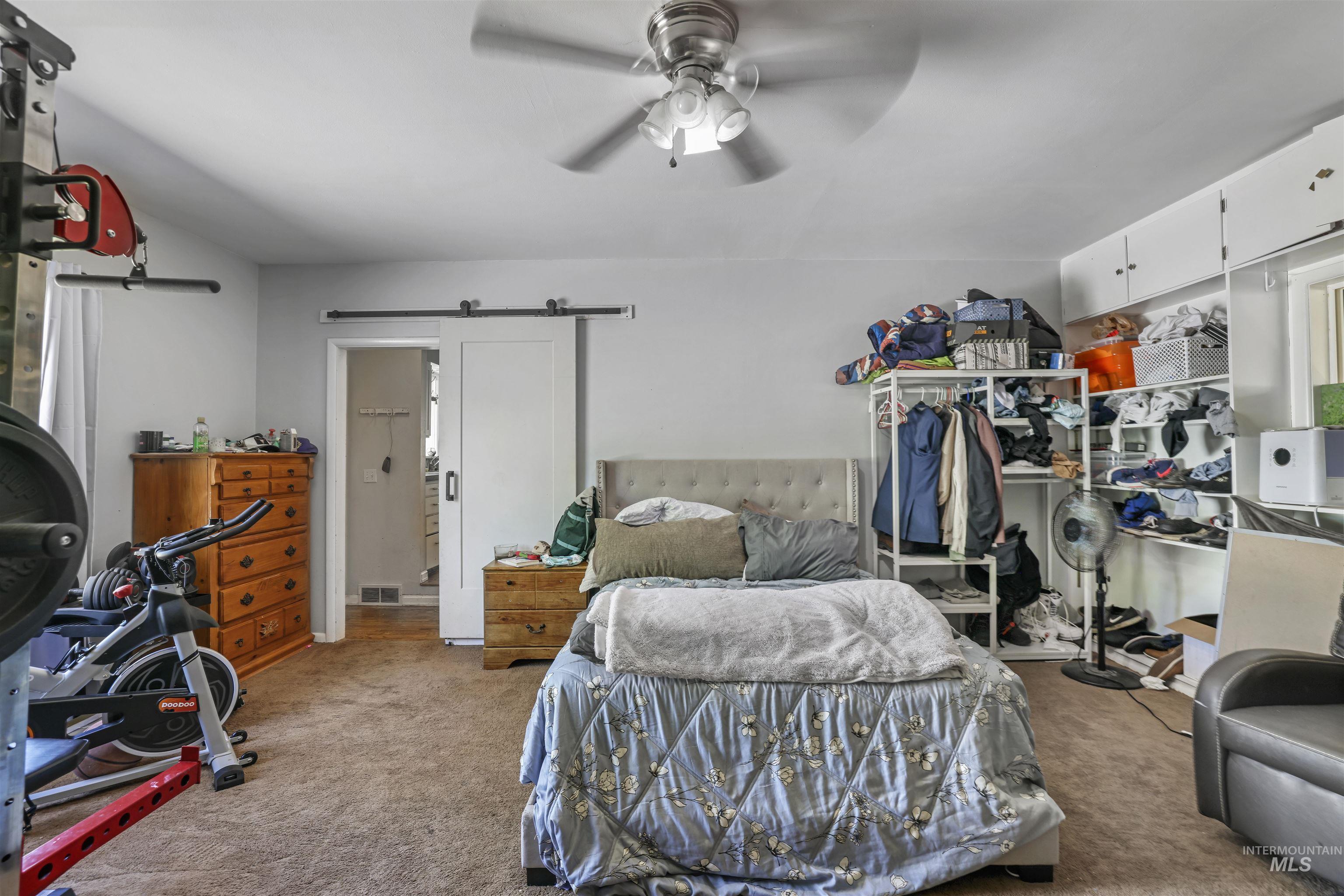 201 West 19th Street Burley, ID 83318 - Photo 26 of 31 Bedroom with a barn door, carpet flooring, a ceiling fan, and ensuite bathroom