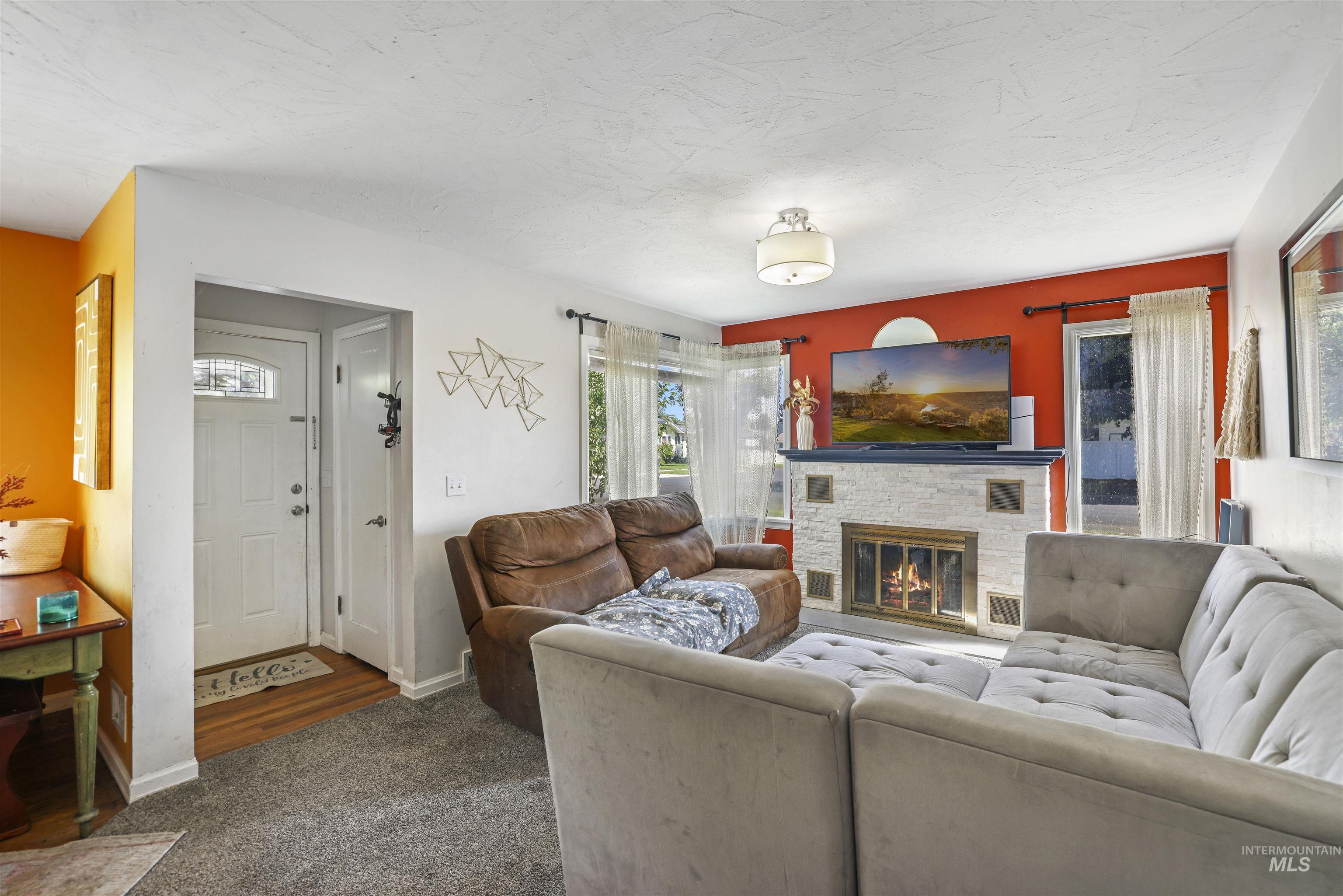 201 West 19th Street Burley, ID 83318 - Photo 4 of 31 Living room featuring a stone fireplace and dark colored carpet
