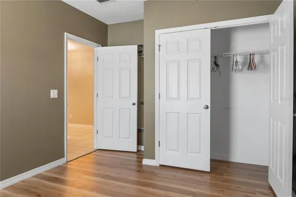 a view of an empty room with wooden floor and a bathroom