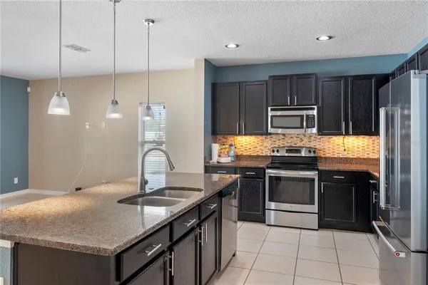 a kitchen with kitchen island granite countertop a sink stove and refrigerator