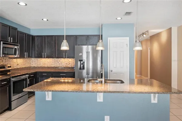 a kitchen with stainless steel appliances granite countertop a sink a stove and a refrigerator