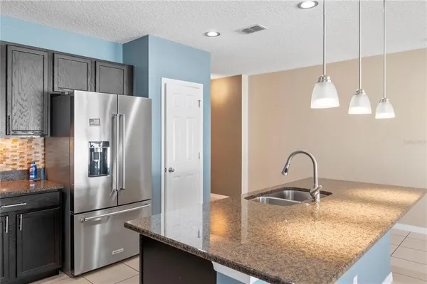 a kitchen with stainless steel appliances granite countertop a refrigerator a sink and a stove