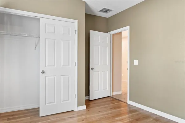 an empty room with wooden floor and closet area