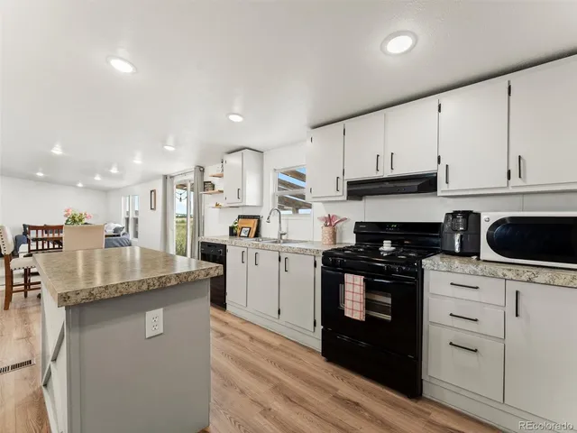 a kitchen with stainless steel appliances granite countertop a stove a sink and white cabinets