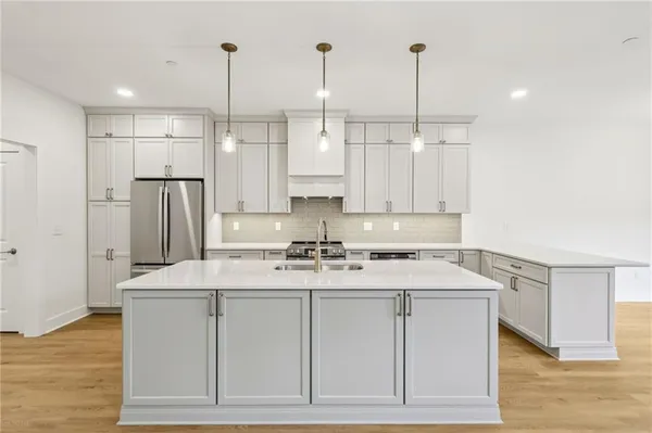 a kitchen with stainless steel appliances granite countertop a sink a stove a refrigerator and island with wooden floor