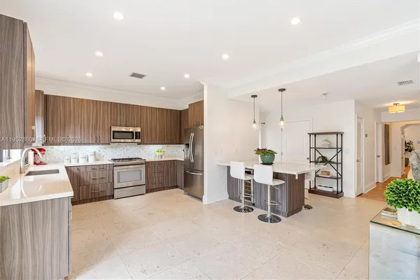 a large white kitchen with lots of counter space and stainless steel appliances