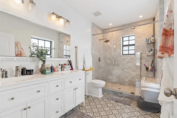 a bathroom with a granite countertop sink a toilet a mirror and shower