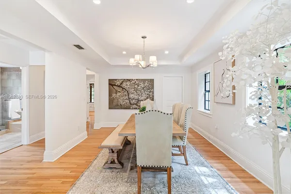 a dining room with wooden floor and chandelier