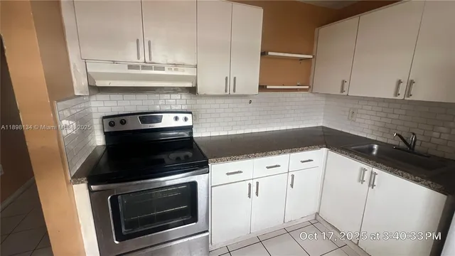 a kitchen with granite countertop white cabinets and appliances