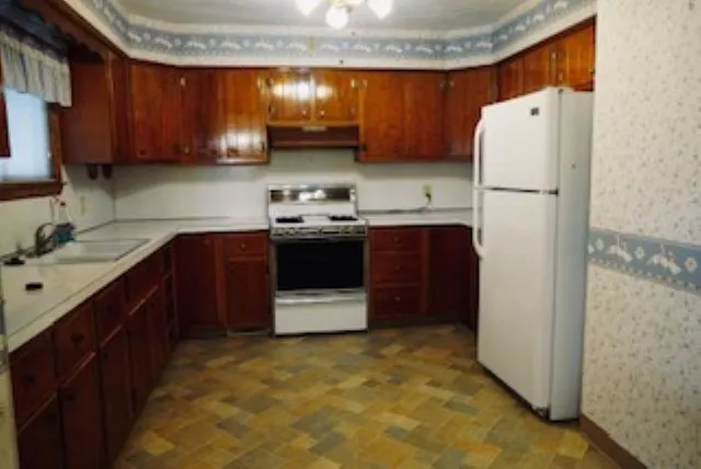 a kitchen with stainless steel appliances granite countertop a refrigerator a sink and a stove