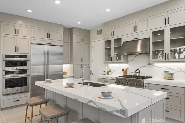 a kitchen with stainless steel appliances a sink a stove a refrigerator cabinets and dining table