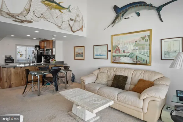 a living room with furniture a table and kitchen view