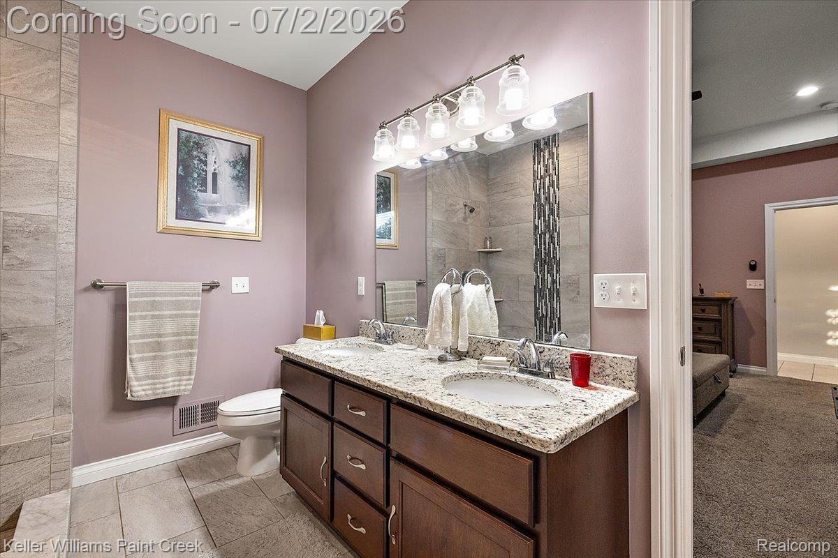 54230 Card Road Macomb, MI 48042 - Photo 51 of 73 Bathroom vanity featuring a dual-sink granite countertop, dark wood-finish cabinetry with silver-tone hardware, and an overhead vanity light fixture