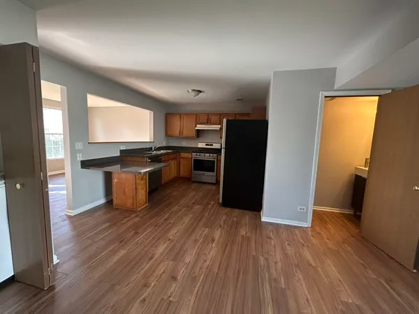 a kitchen with stainless steel appliances granite countertop a refrigerator a sink dishwasher a stove and white countertops with wooden floor