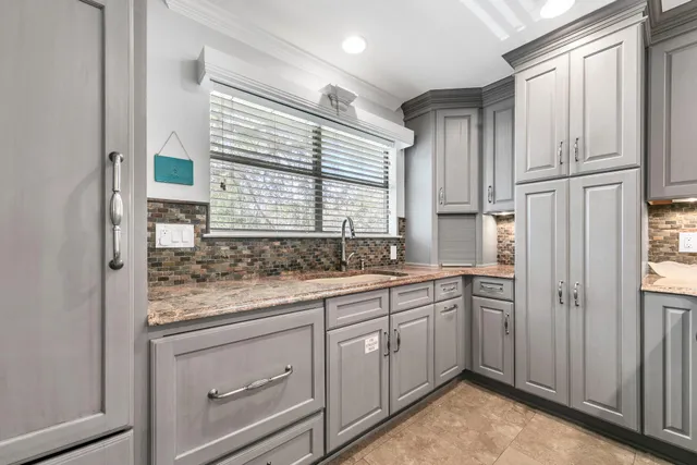 a spacious bedroom with a bed a dresser and a chandelier