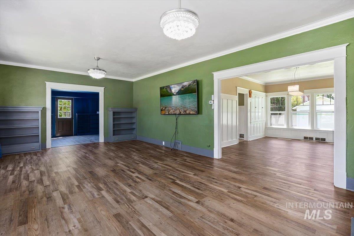 813 7th Street Rupert, ID 83350 - Photo 7 of 48 Open-concept living area featuring wood-finish flooring, two distinct chandelier light fixtures, and built-in shelving units