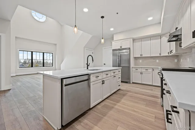 a kitchen with a sink window and stainless steel appliances