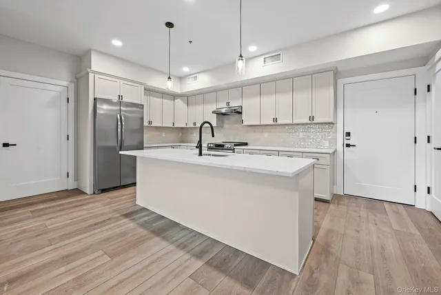 a kitchen with kitchen island a sink stainless steel appliances and cabinets